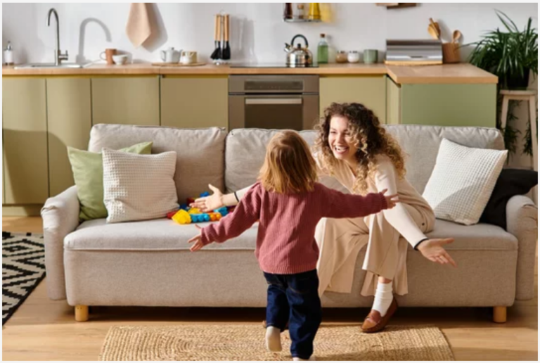 Toddler running toward a smiling mother on a couch