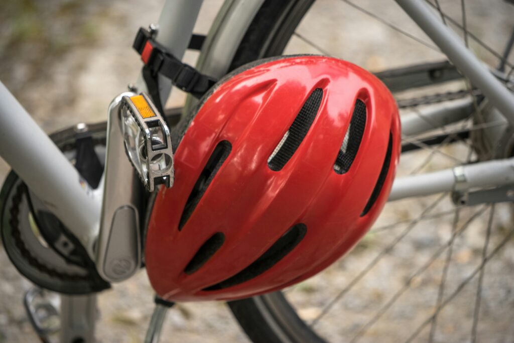 Red bicycle helmet hanging on a bike, representing safety and protection against head injuries from defective products.
