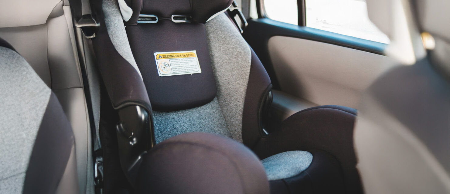 Child car seat installed in the back seat of a car, representing a defective seat that failed to protect a child in a side-impact collision.
