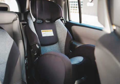 Child car seat installed in the back seat of a car, representing a defective seat that failed to protect a child in a side-impact collision.