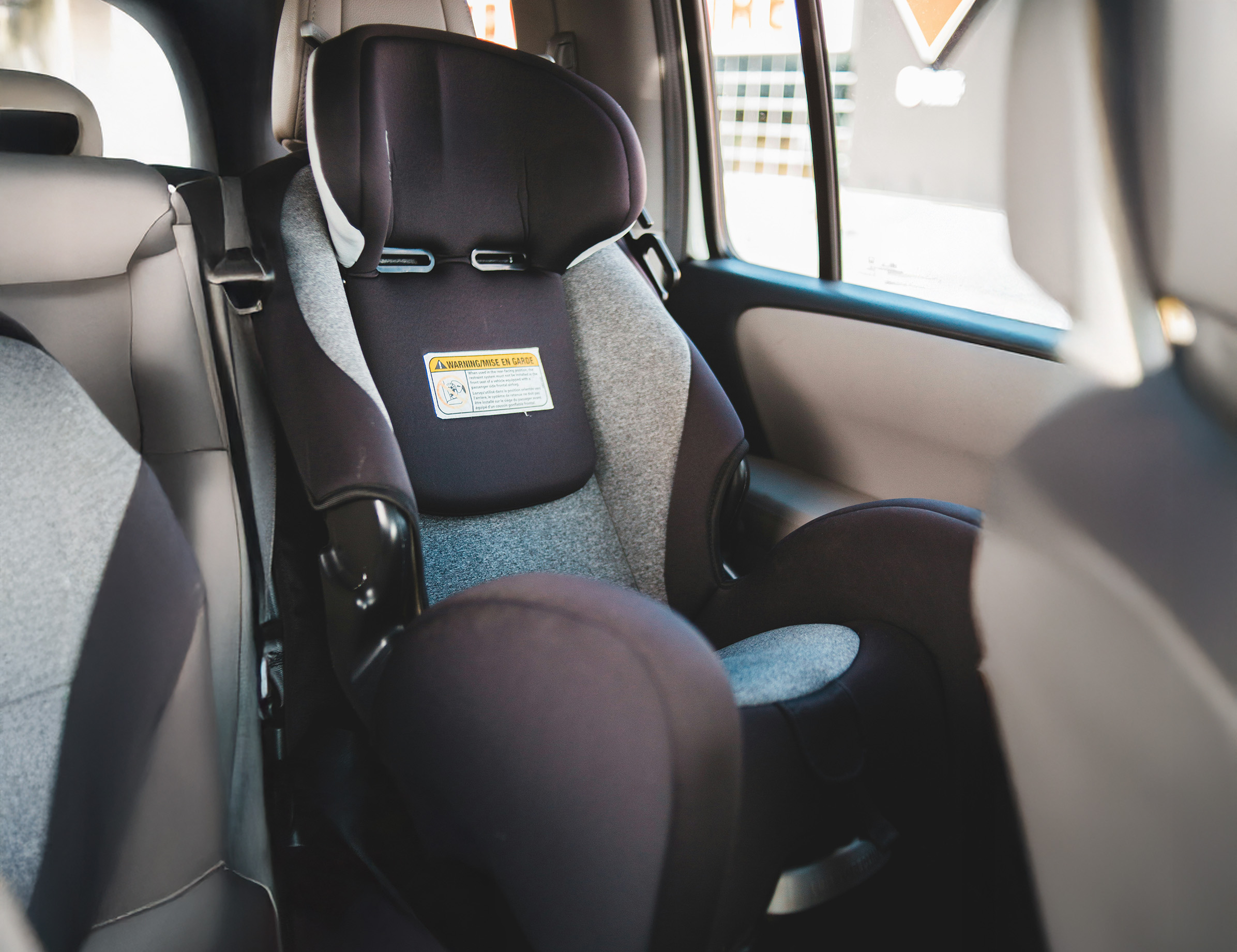 car-seat Child car seat installed in the back seat of a car, representing a defective seat that failed to protect a child in a side-impact collision.