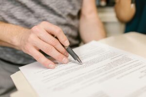 Close-up of a person reviewing and signing legal documents, representing accountability and legal action in defective product cases.