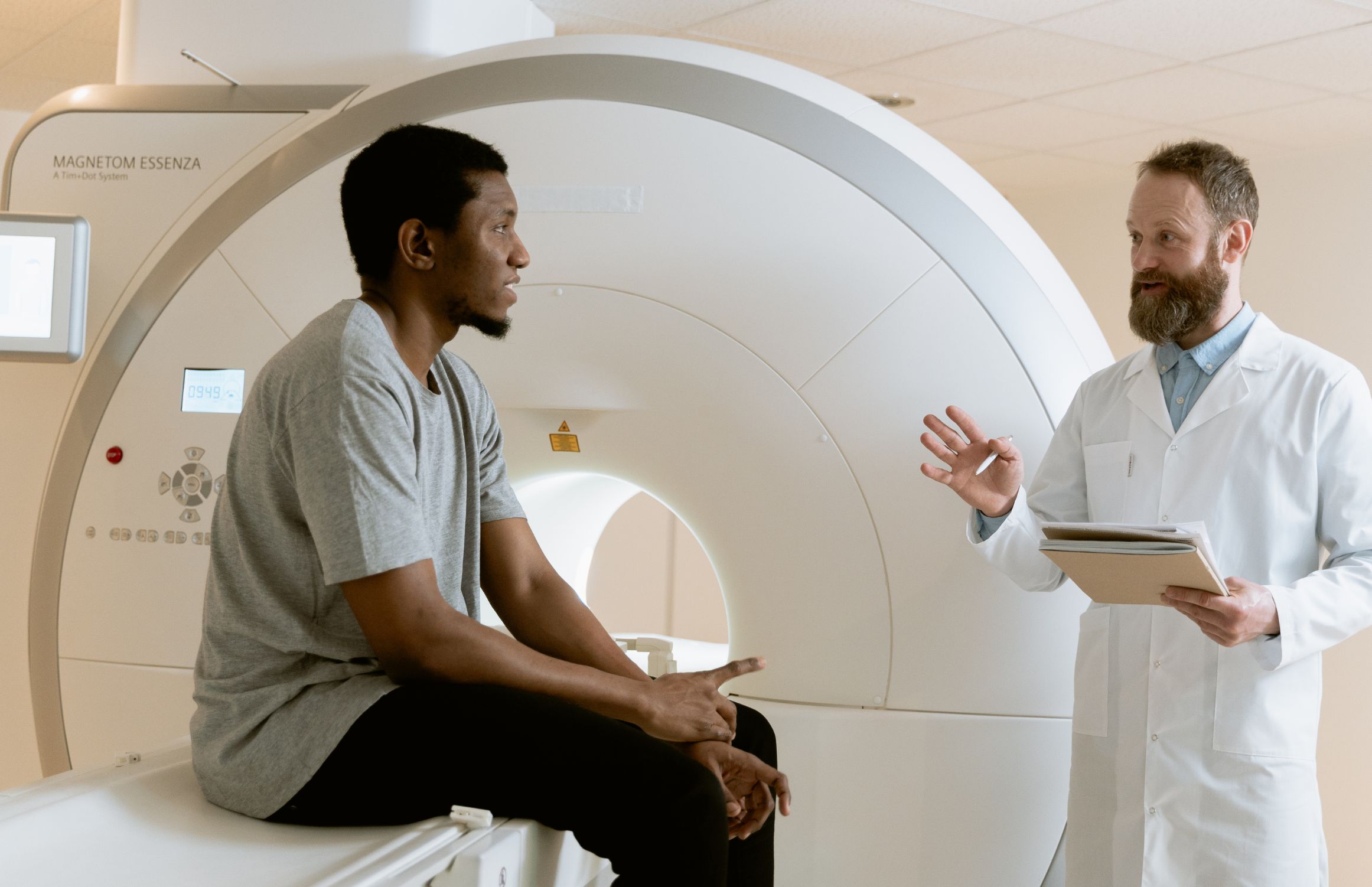 A doctor speaking with a patient seated on an MRI machine before a diagnostic brain scan.