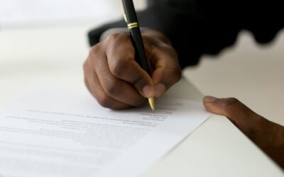 Hand signing policy paperwork, representing insurance coverage decisions.