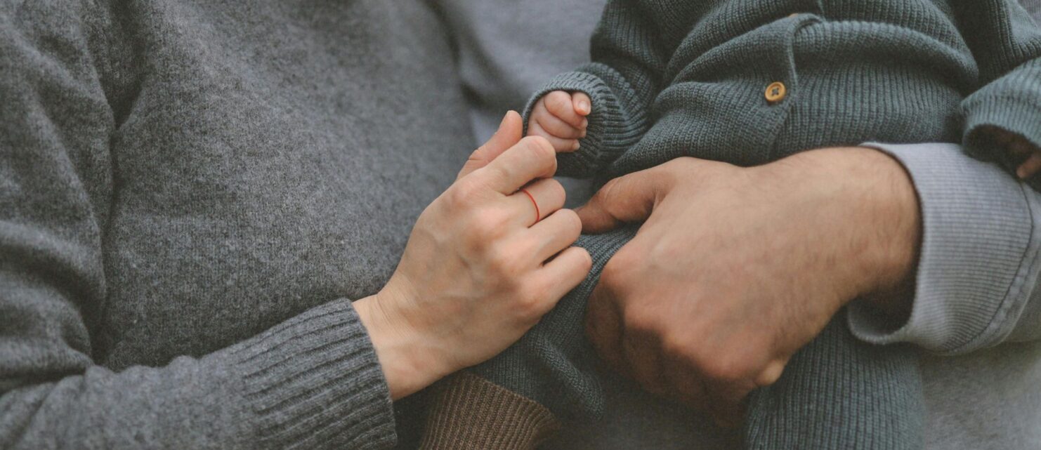 Parents holding a baby’s hand