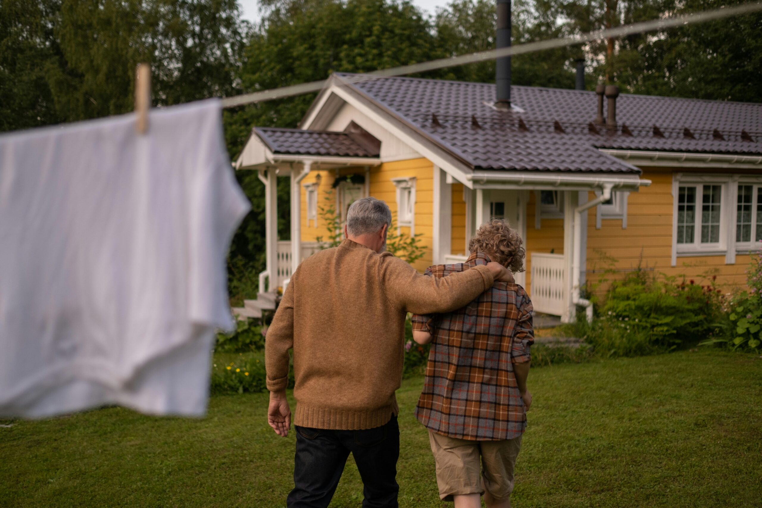 Father and son embrace in a hug while walking towards house