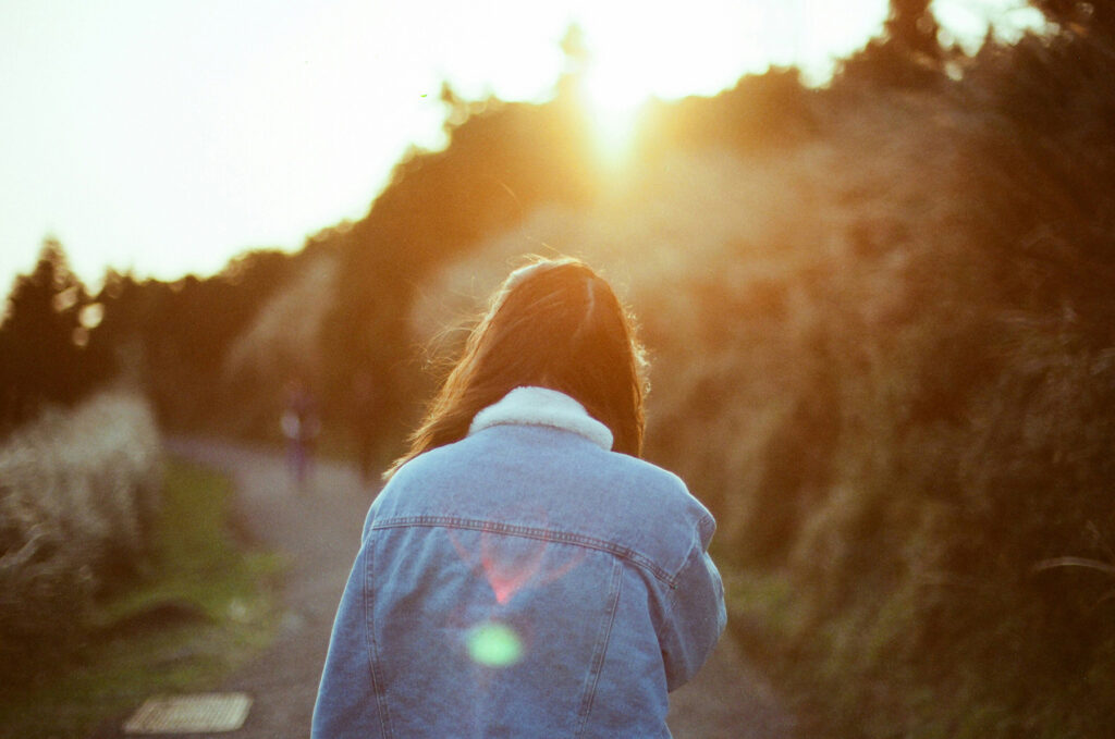 Women Seen from behind walking down the road with sun setting