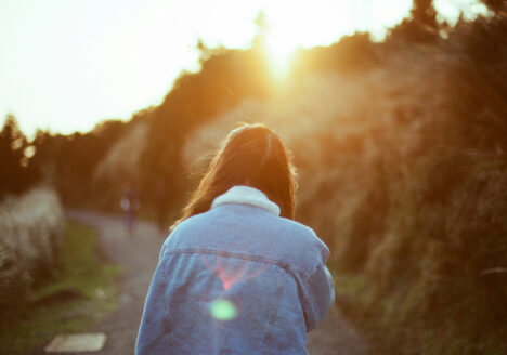 Women Seen from behind walking down the road with sun setting
