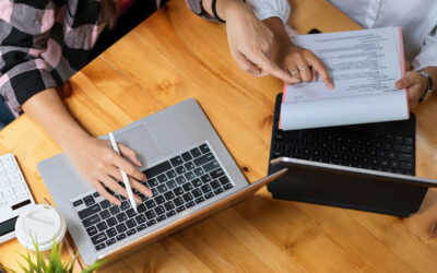 Blog-Hero-TBI-and-School-IEPs-504-Plans-and-Educational-Rights Two people sit at a table looking at paper records and a laptop