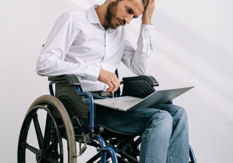 Man in a wheelchair using a laptop, representing assistive technology and independence after a TBI