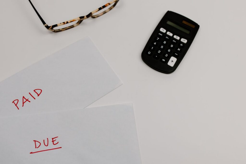 Calculator and paid/due bills on a desk, representing the lifetime financial cost of traumatic brain injury and spinal cord injury