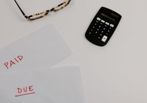 Calculator and paid/due bills on a desk, representing the lifetime financial cost of traumatic brain injury and spinal cord injury