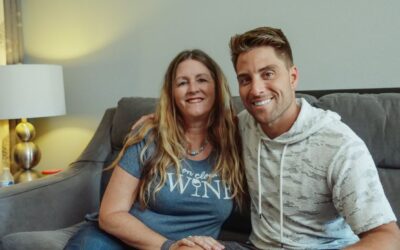 A mother and her adult son sitting together on a couch at home, representing family support during the transition to adulthood after a childhood brain injury